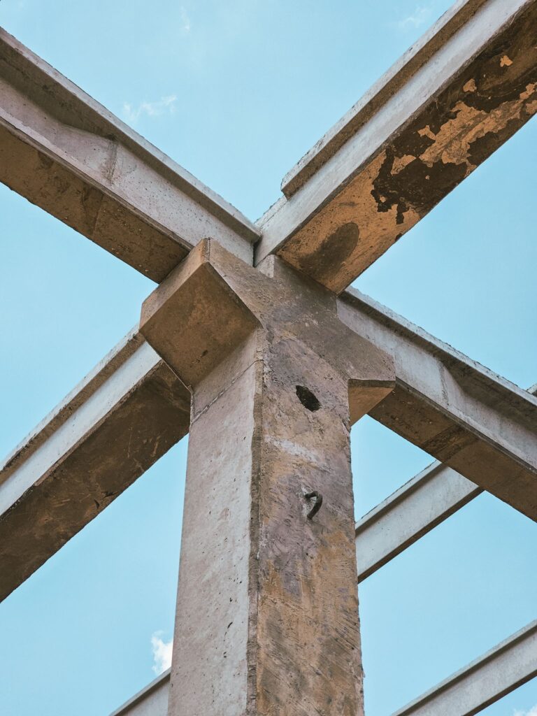 Upward view of a concrete framework under construction with clear blue sky background.